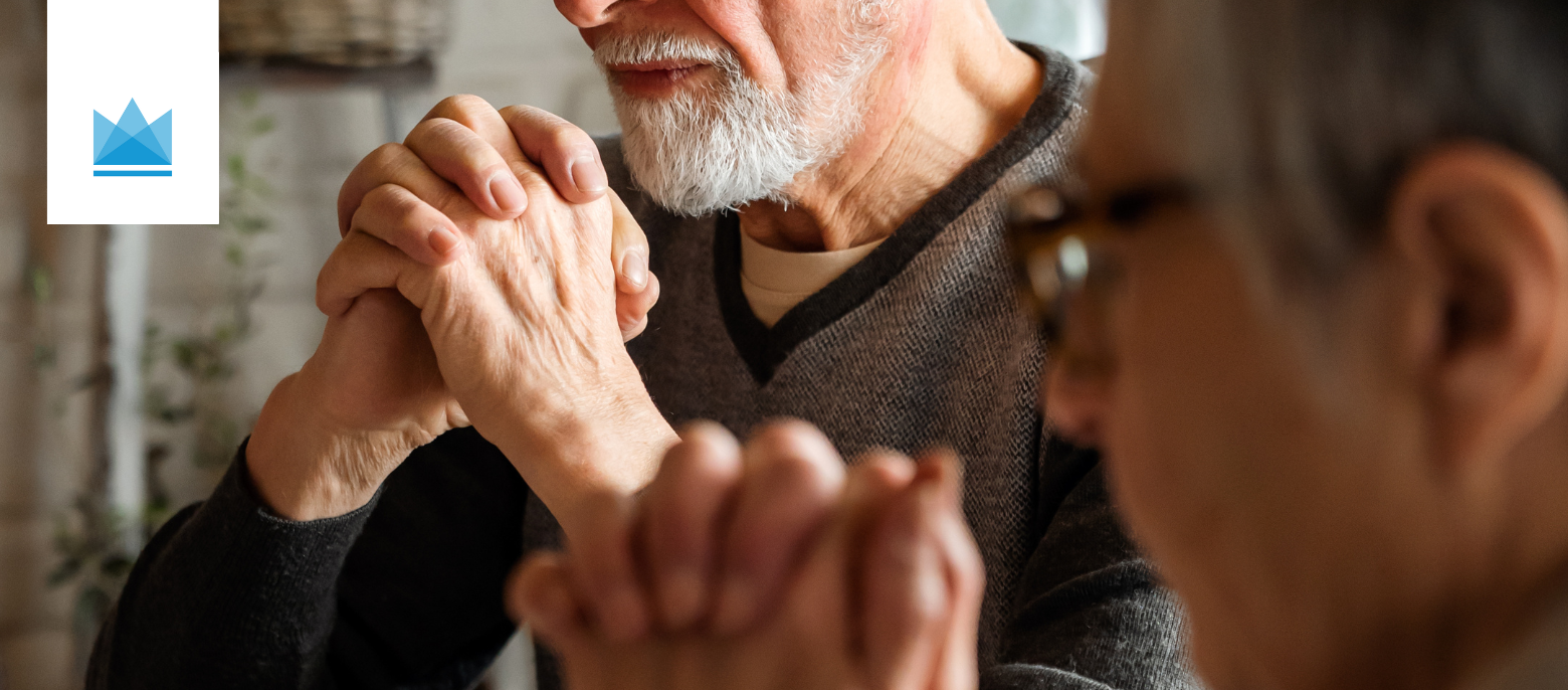 close up of older man and woman with their hands clasped and praying